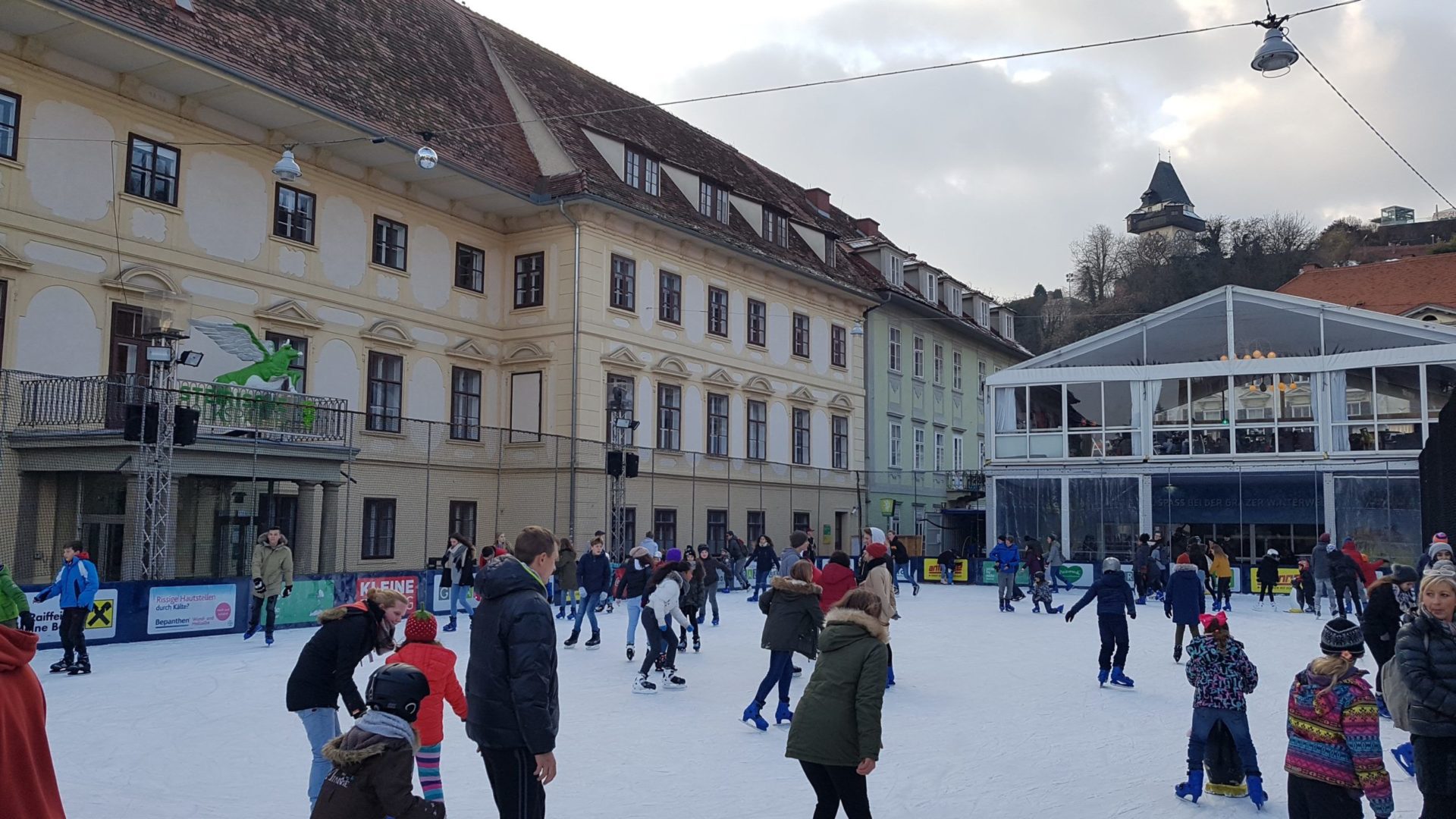 Schlittschuhlaufen auf dem Karmeliterplatz in Graz, Österreich.